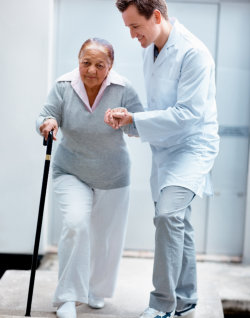 caregiver assisting senior woman to walk